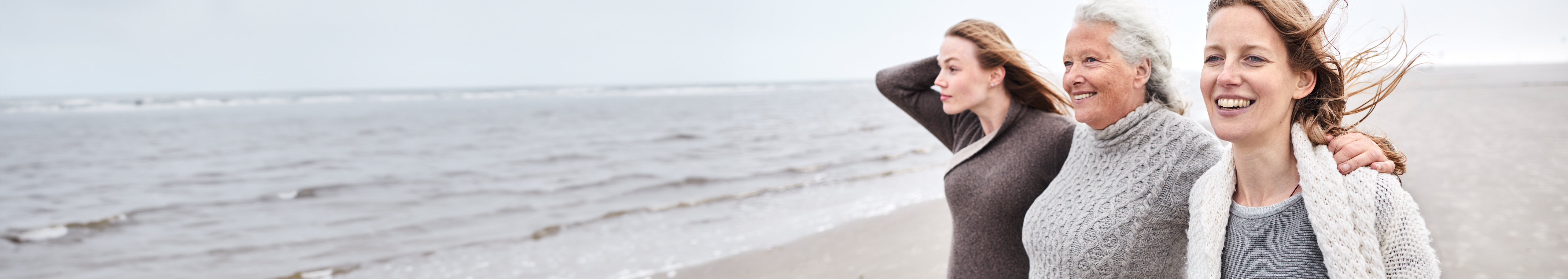three women beach hug happy
