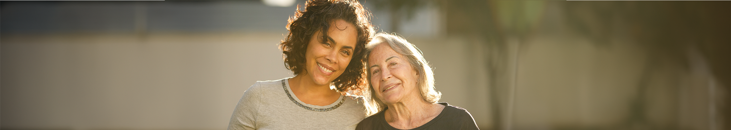 An Aboriginal woman in her 40s and a wise older woman in her 60s, smiling together, empowered to have a free breast screen.