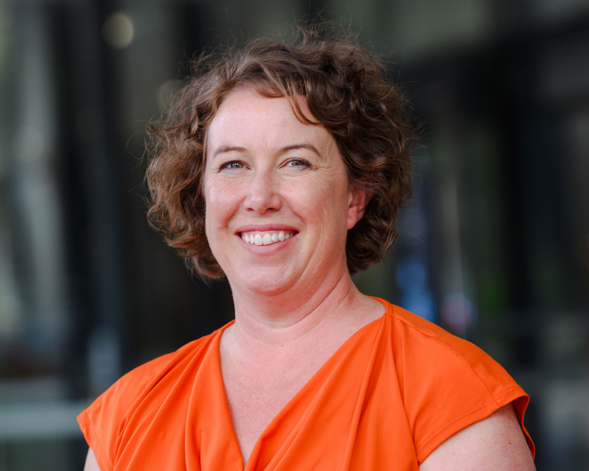 Portrait of A woman smiling wearing an orange top